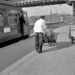 166729 Afbeelding van een kruier op het perron van het N.S.-station Amsterdam C.S. te Amsterdam, met links een ...